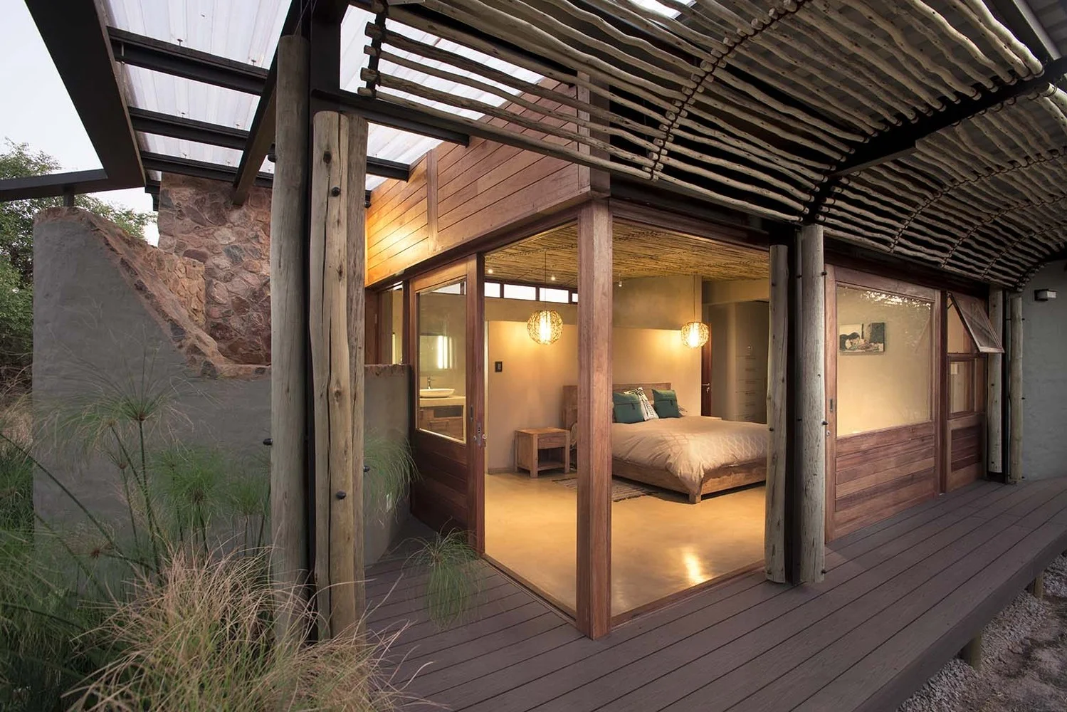 Bush Residence bedroom suite with sliding glass doors opening onto a timber deck
